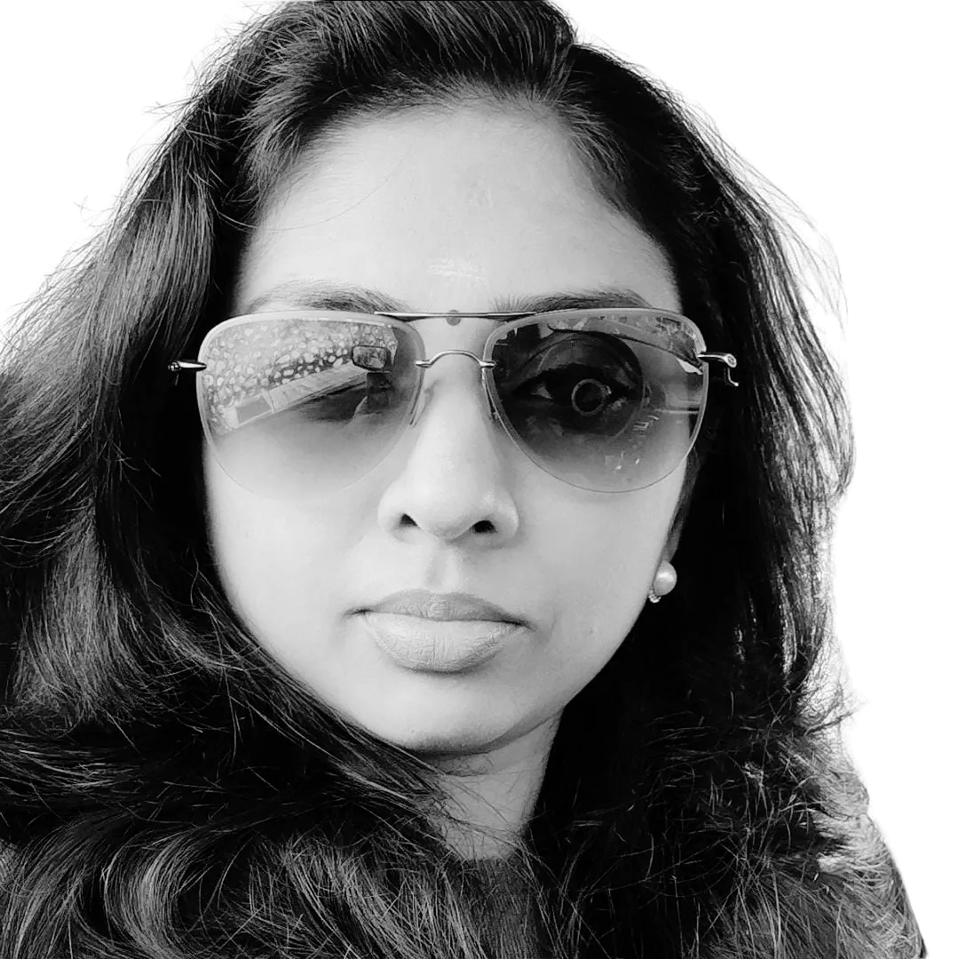 A person wearing sunglasses and a confident expression in a black and white photo.